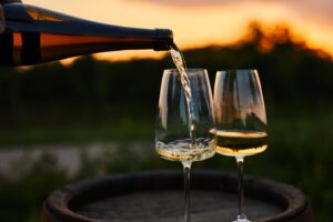 Weißwein in Gläser auf einem alten Fass gießen, Weinprobe